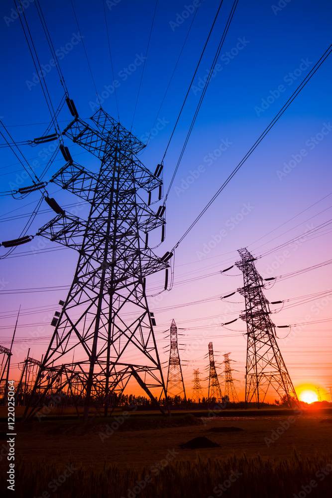 Fototapeta premium The silhouette of the evening electricity transmission pylon