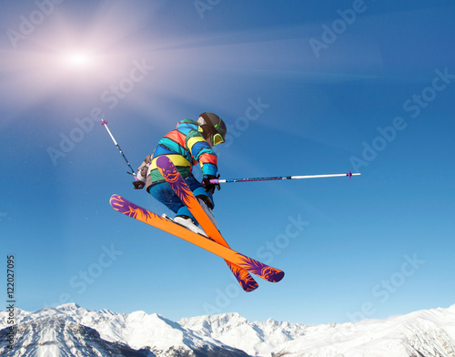 Skifahrer springt vor blauem Himmel und Sonne