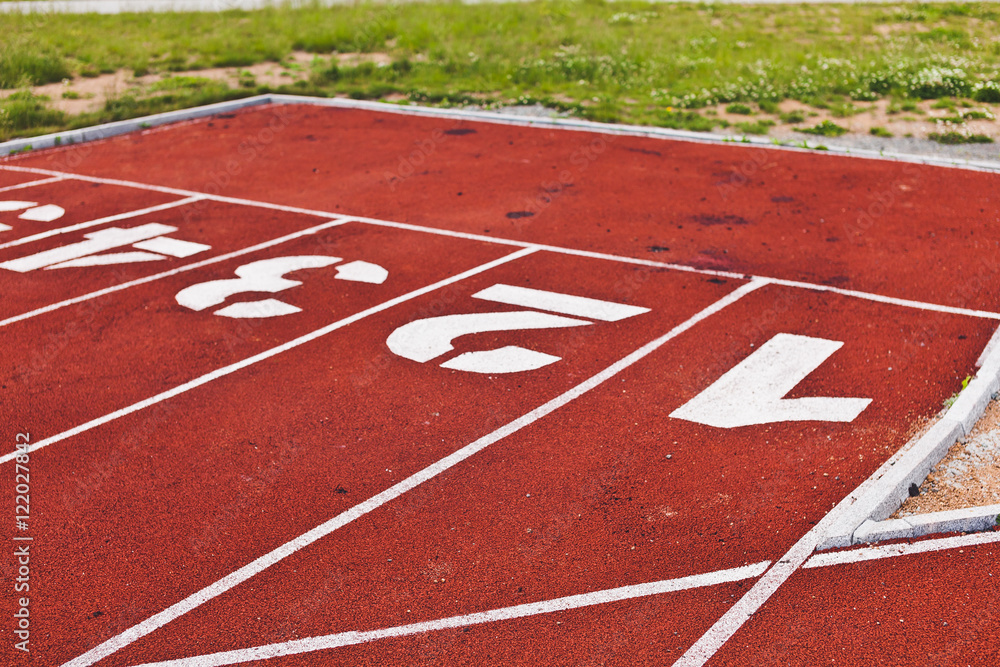 Rugged starting line with digits on stadium, red running path