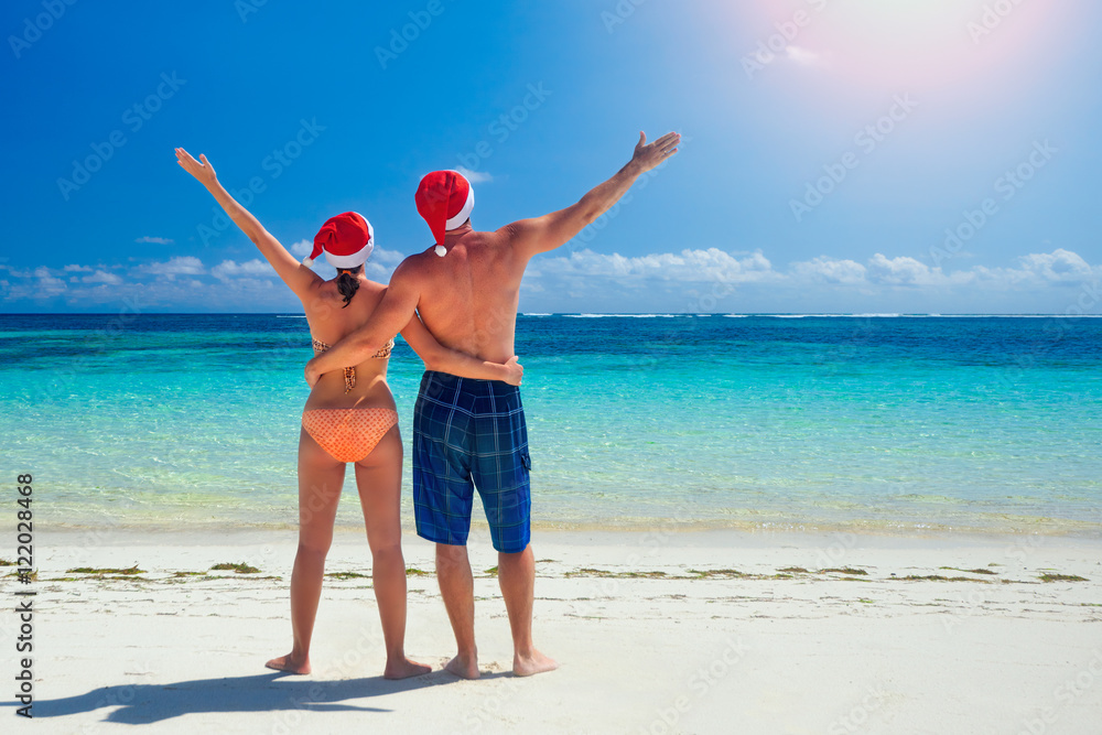Couple in santa's hats on a tropical beach Couple in santa's hats on a tropical beach