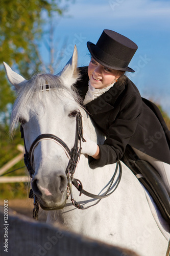 Smiling woman riding on a white horse