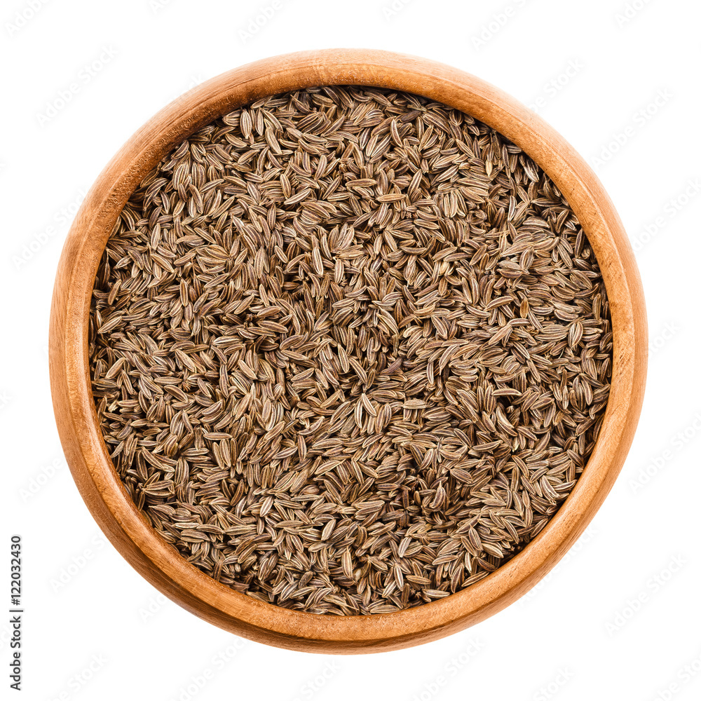 Caraway seeds in wooden bowl on white background. Dried whole fruits of Persian cumin, Carum carvi, with anise like flavor and aroma used as spice in cuisine. Isolated macro photo close up from above. Caraway seeds in wooden bowl on white background. Dried whole fruits of Persian cumin, Carum carvi, with anise like flavor and aroma used as spice in cuisine. Isolated macro photo close up from above.