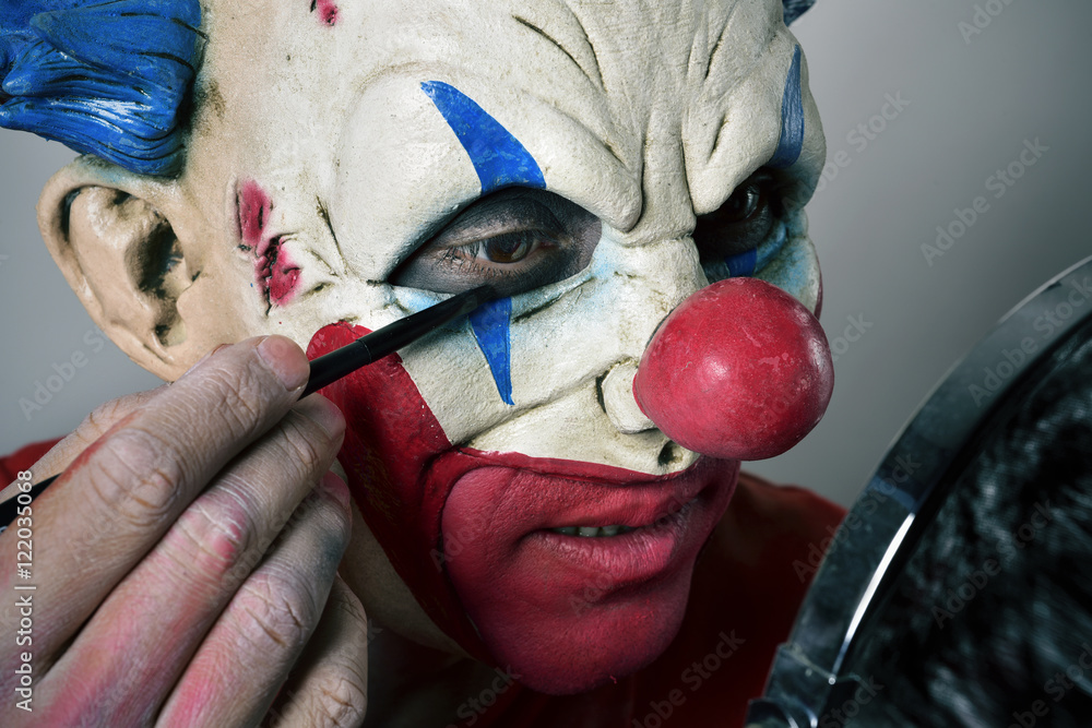 Naklejka premium young man making up himself as an evil clown
