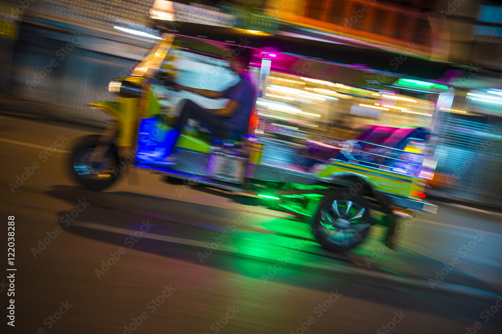 Bangkok Thailand tuk-tuk taxi zooms by in a brightly colored lights night blur