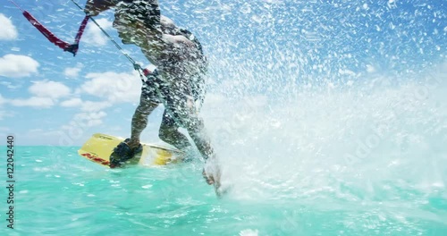 Young man kitesurfing in tropical blue ocean, extreme sport slow motion