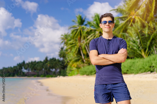 Sunny day on the seaside. Handsome young confident man standing on the beach.