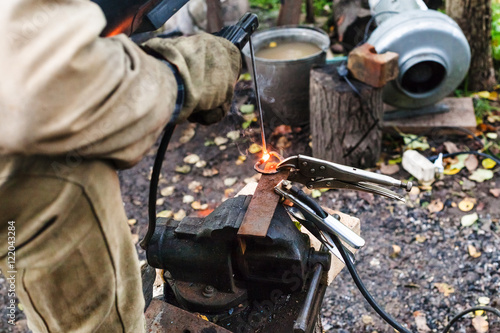 Welder welds iron ring by spot electric welding