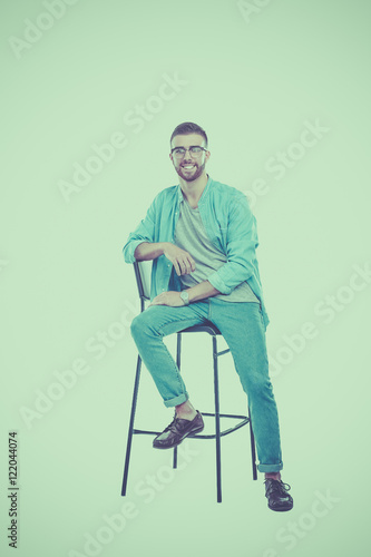 Young man sitting on the chair isolated over white background © lenets_tan