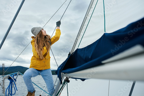 Young strong woman sailing the boat