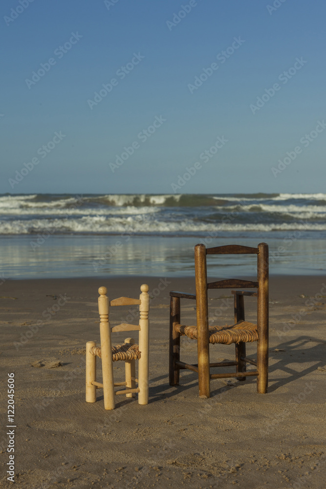 Rear view small wicker chairs stand up in the seashore Rear view small wicker chairs stand up in the seashore