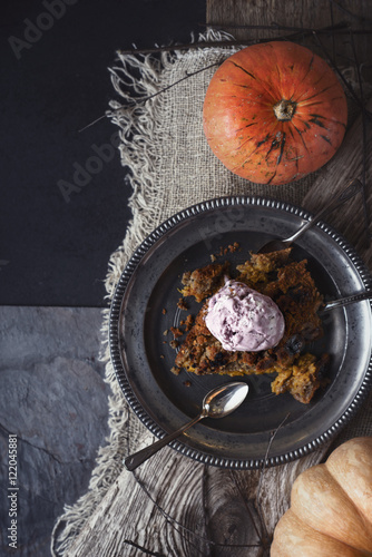 Pumpkin dump cake with ice cream on the metal plate on the stone table  vertical