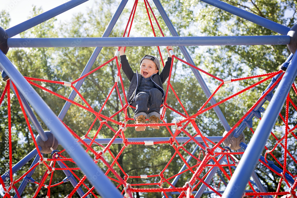 Happy little child boy climbed on playground