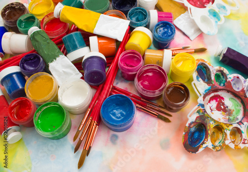 Paints, brushes and palette on the colorful background. The workplace of the artist. Banner for school