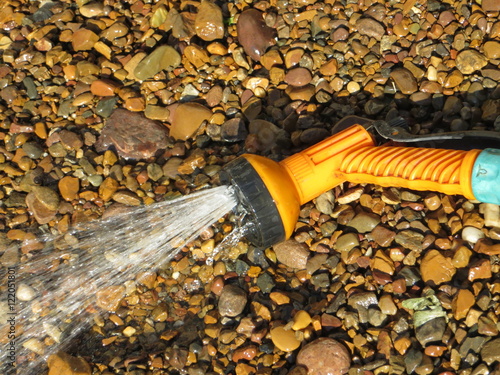 Washing river pebble  with an adjustable shower (spray) in the summer garden photo