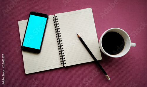 Tea in white cup with Journal book and smartphone