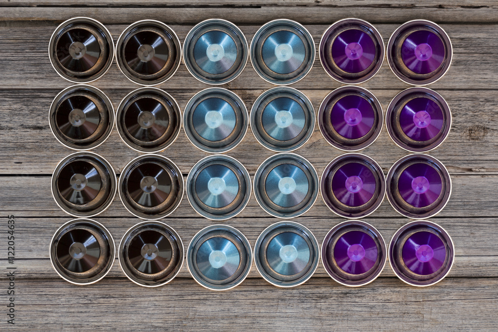 Italian espresso coffee capsules or coffee pods on wood background with some roasted coffee beans Italian espresso coffee capsules or coffee pods on wood background with some roasted coffee beans