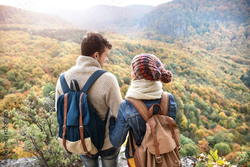 Beautiful couple with backpacks against colorful autumn forest