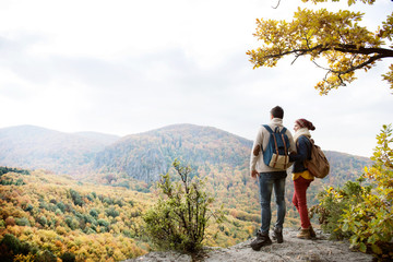 Beautiful couple with backpacks against colorful autumn forest