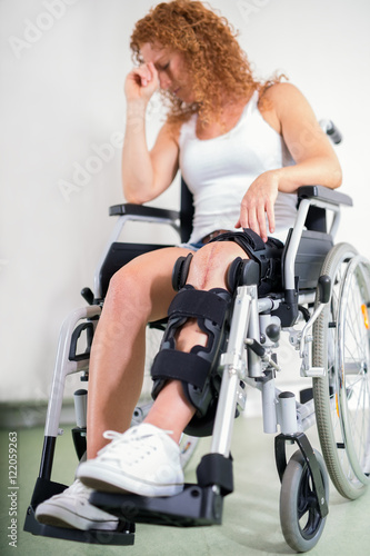 Dejected woman with her knee in a brace.