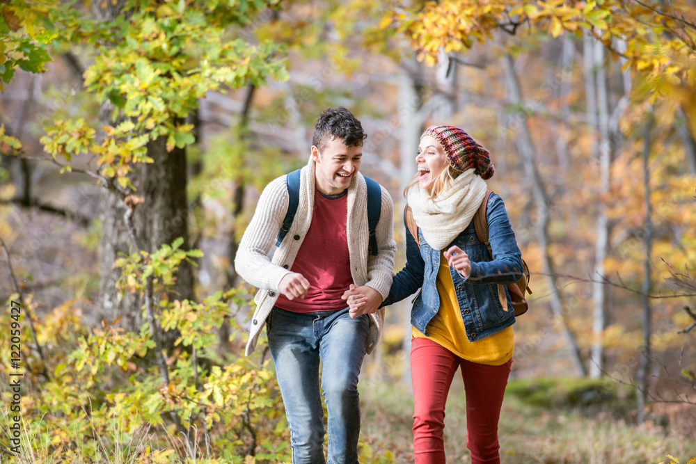 Fototapeta premium Beautiful couple on a walk in sunny autumn forest