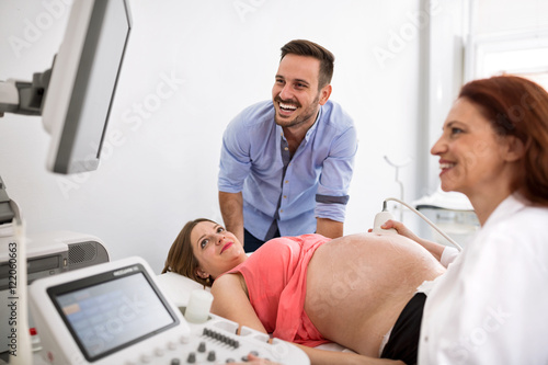 Happy couple looking at ultrasound results with doctor