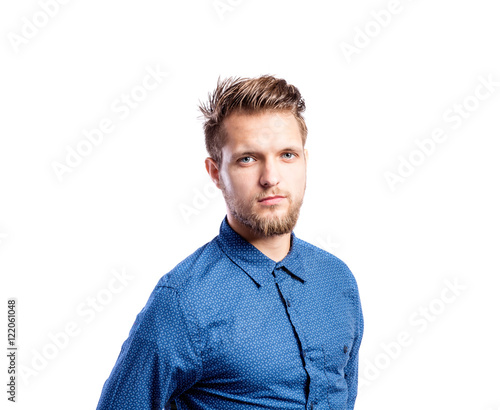 Hipster man in blue long-sleeved shirt, studio shot, isolated