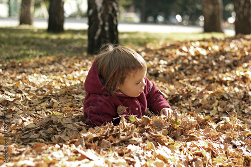 Cute little child lies in the leaves in an autumn park