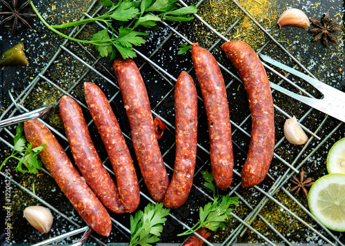 Raw sausages merguez, on a black background, with spices on the gridiron