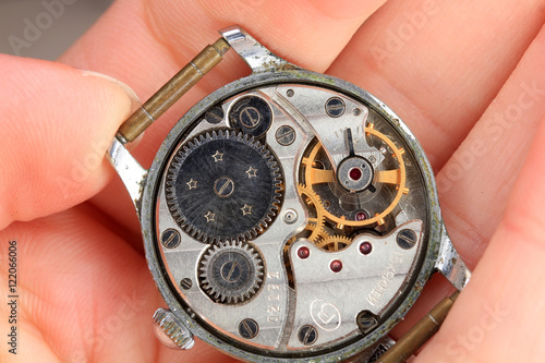 old clock with cogs and gears lying on the palm of your hand