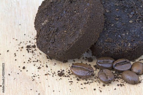Used coffee grounds after espresso machine and coffee beans on wooden background. Macro image.