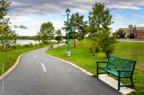 Windinìg Riverside Path Lined with Benches and Trees photo