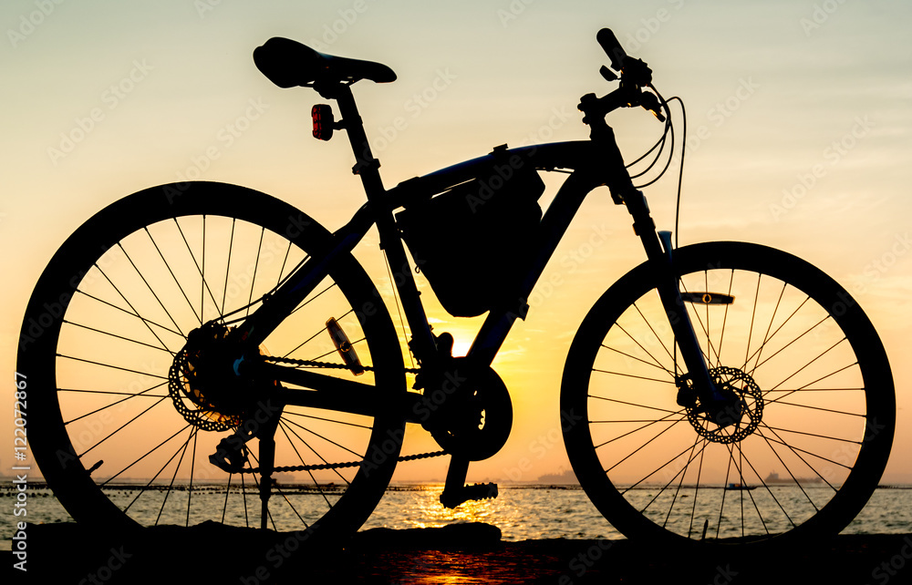 Silhouette of mountain bike at sea with sunset sky background Silhouette of mountain bike at sea with sunset sky background