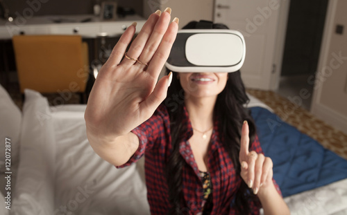 Woman in virtual reality helmet on bed. VR glasses.