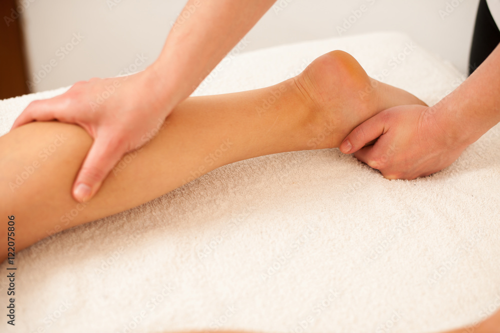 Therapist massaging a leg in a wellness center - spa Therapist massaging a leg in a wellness center - spa