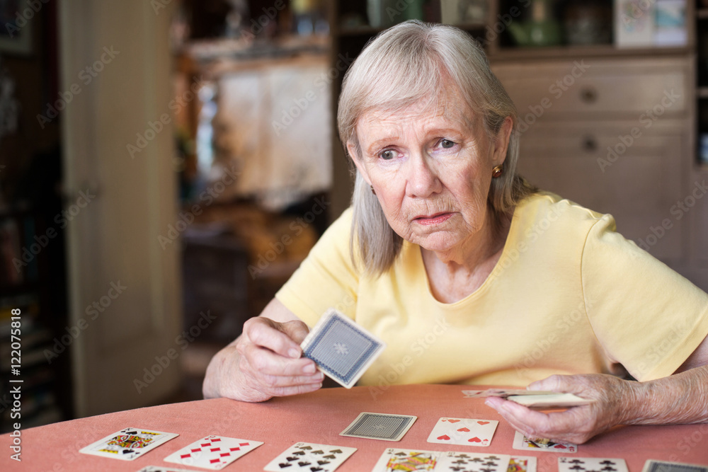 Worried woman playing cards at table