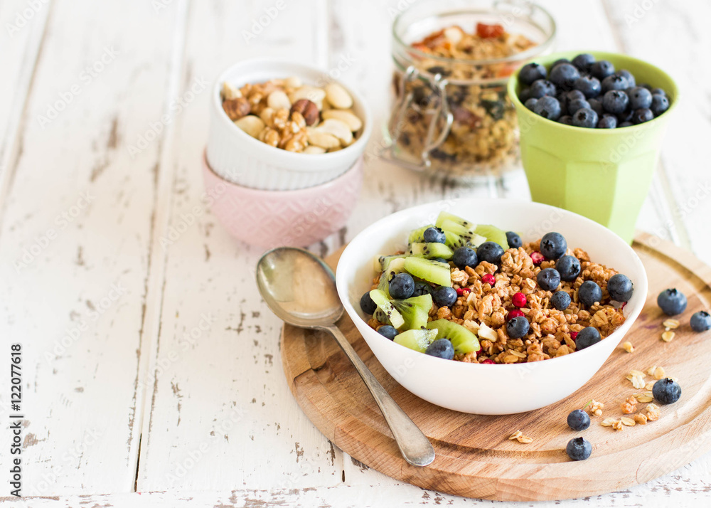 Healthy breakfast; Homemade granola with kiwi, blueberries and nuts in white bowl Healthy breakfast; Homemade granola with kiwi, blueberries and nuts in white bowl