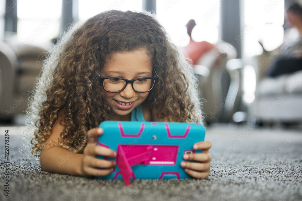 Girl playing handheld video game while lying on carpet at home Girl playing handheld video game while lying on carpet at home