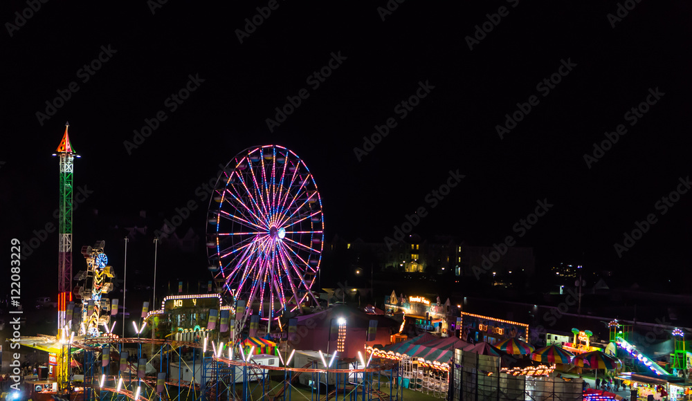 view of the county fair at night with colorful lit rides
