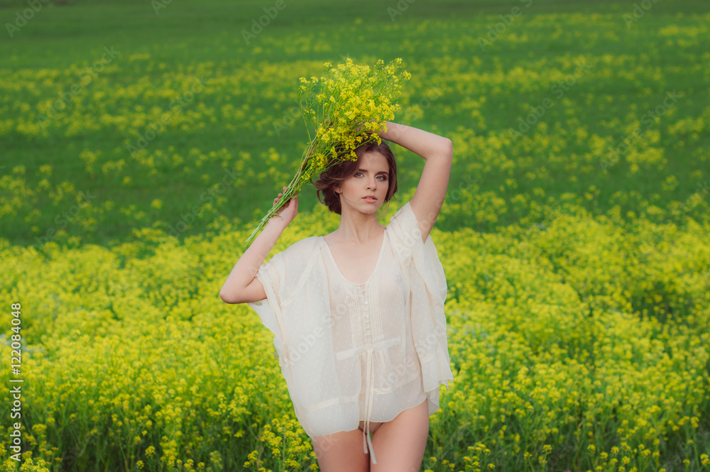 Portrait of young beautiful girl in field with bouquet of yellow flowers in hands above the head and looking to the camera Portrait of young beautiful girl in field with bouquet of yellow flowers in hands above the head and looking to the camera