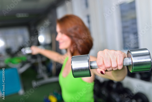 fitness, sport, training and lifestyle concept - middle aged woman doing exercises with dumbbells at gym