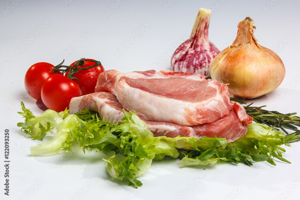 Two pieces of pork loin with salad and vegetables on white backg Two pieces of pork loin with salad and vegetables on white backg