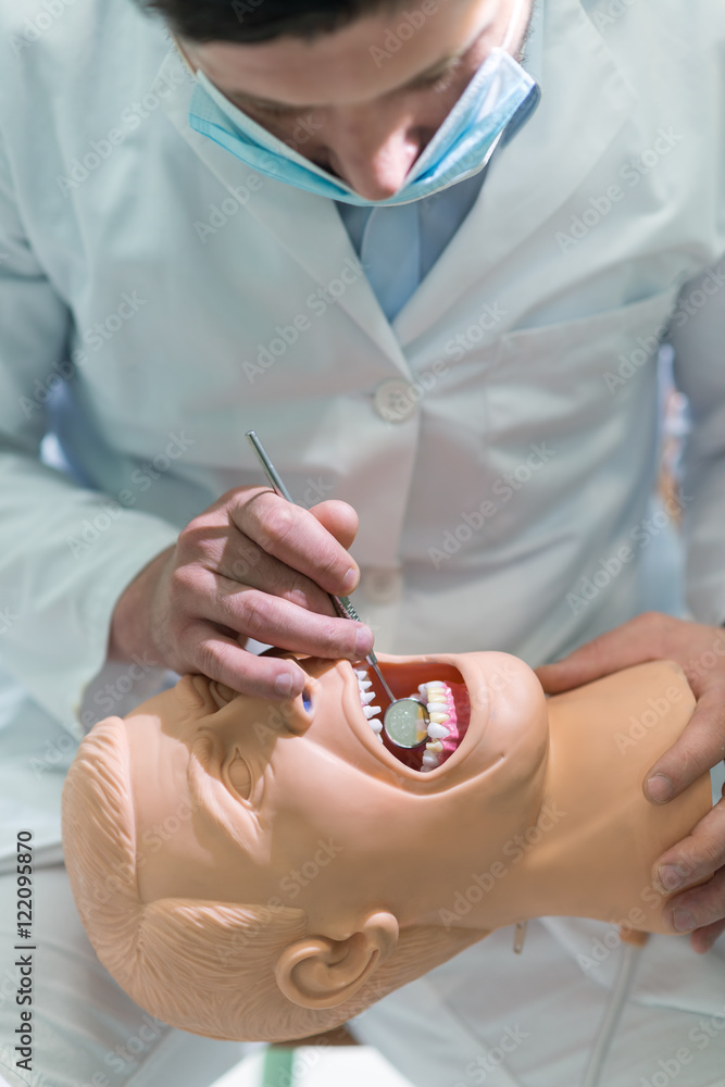 Male dental student practicing on doll. Male dental student practicing on doll.
