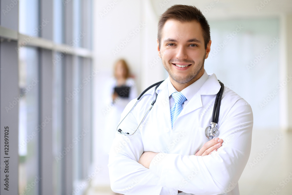 Smiling doctor waiting for his team while standing upright Smiling doctor waiting for his team while standing upright