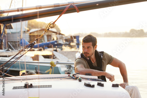 Handsome man on a sailing boat in sunset