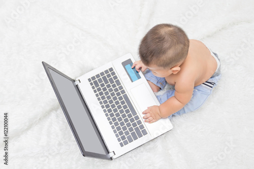 Cute baby boy with laptop on white carpet