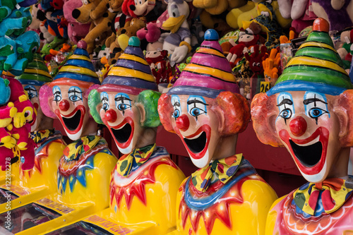 Row of clown heads in carnival side show alley with prizes