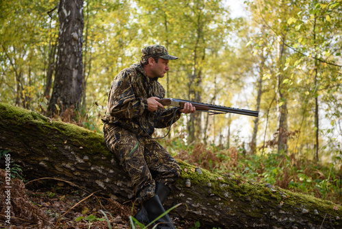 Hunter with a gun in the autumn woods, hunting for a hazel grouse 
