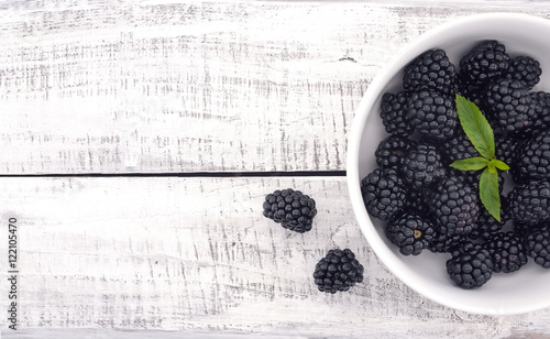 Close up of ripe blackberries in a white ceramic bowl over rusti photo