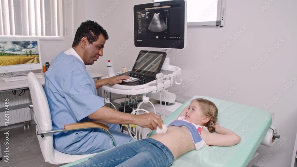 Relaxed little girl lying on examination bed and smiling as Latin-American doctor performing abdominal ultrasound  Stock ビデオ | Adobe Stock 
