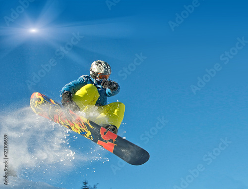 Snowboarder springt vor blauem Himmel und Sonnenschein photo